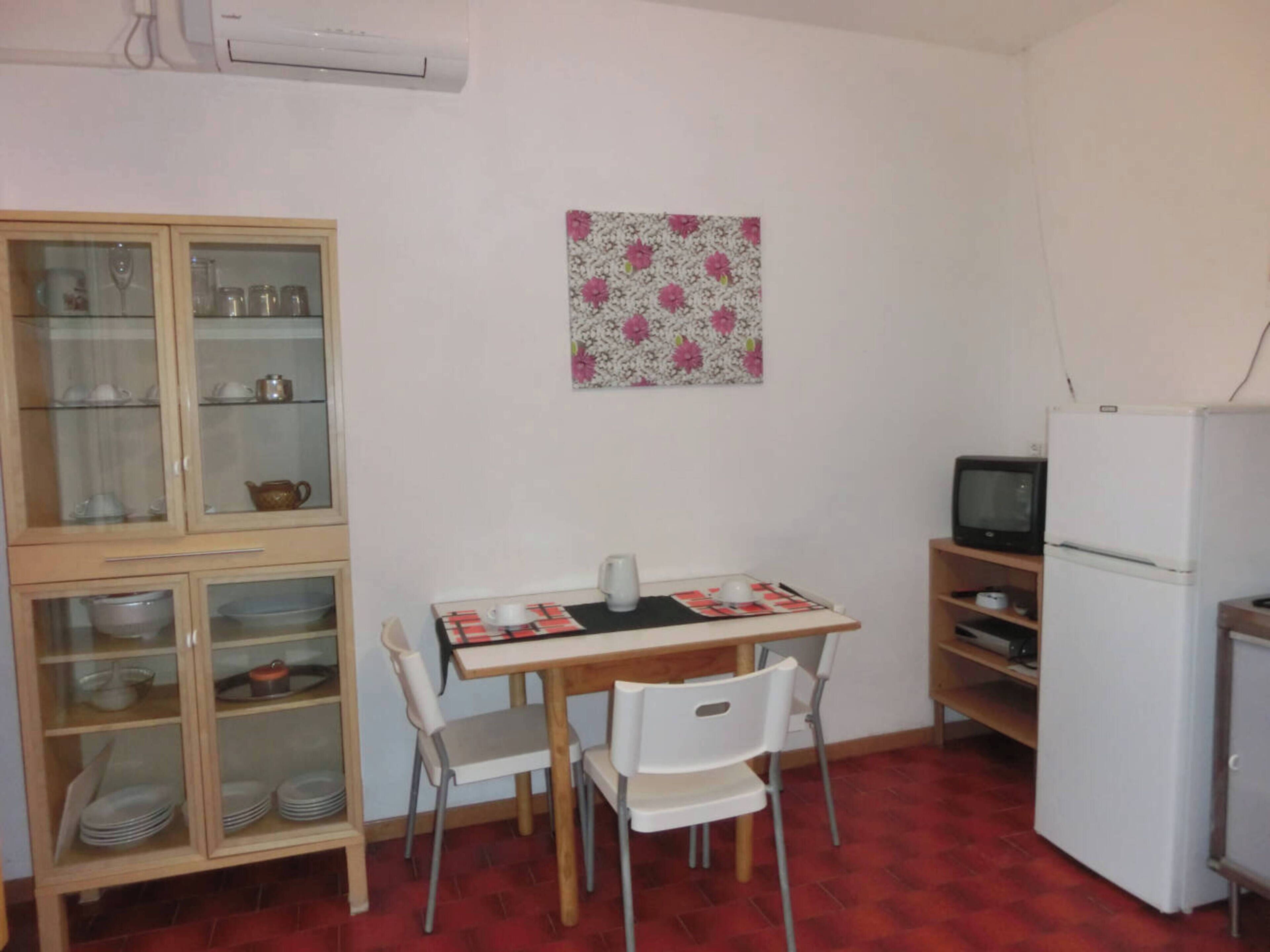 A compact kitchen with a dining table, chairs, a refrigerator, and a microwave.