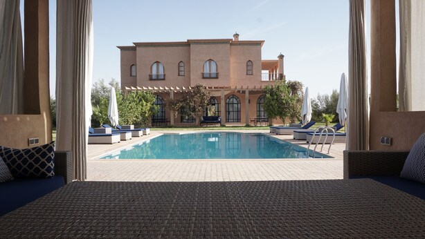 A pool area with lounge chairs and a building in the background. - Saphir Paon - Luxury Villa in the Middle of a Farm (Souihla)
