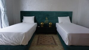 A hotel room with two single beds, a dark green headboard, white bedding, and a decorative rug. - Saphir Paon - Luxury Villa in the Middle of a Farm (Souihla)