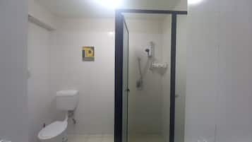 Een kleine, afgesloten douchecel met een glazen deur, een toilet en een handdroger aan de muur.