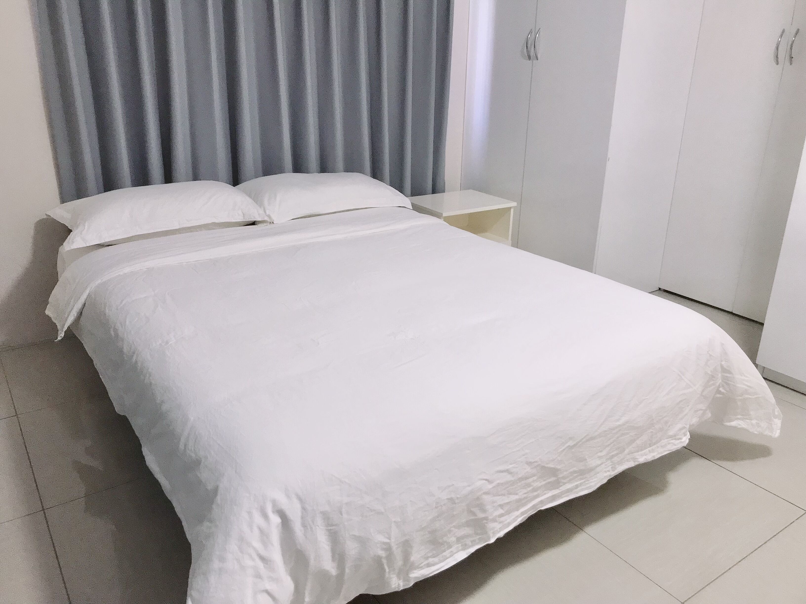 A neatly made bed with white linens in a hotel room.