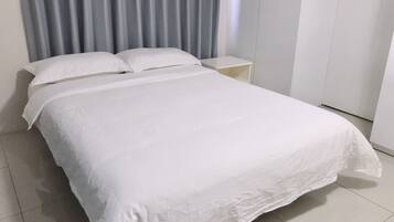 A neatly made bed with white linens in a hotel room.
