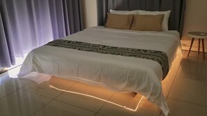 Una cama bien hecha con una manta estampada, una mesita de noche y una lámpara.