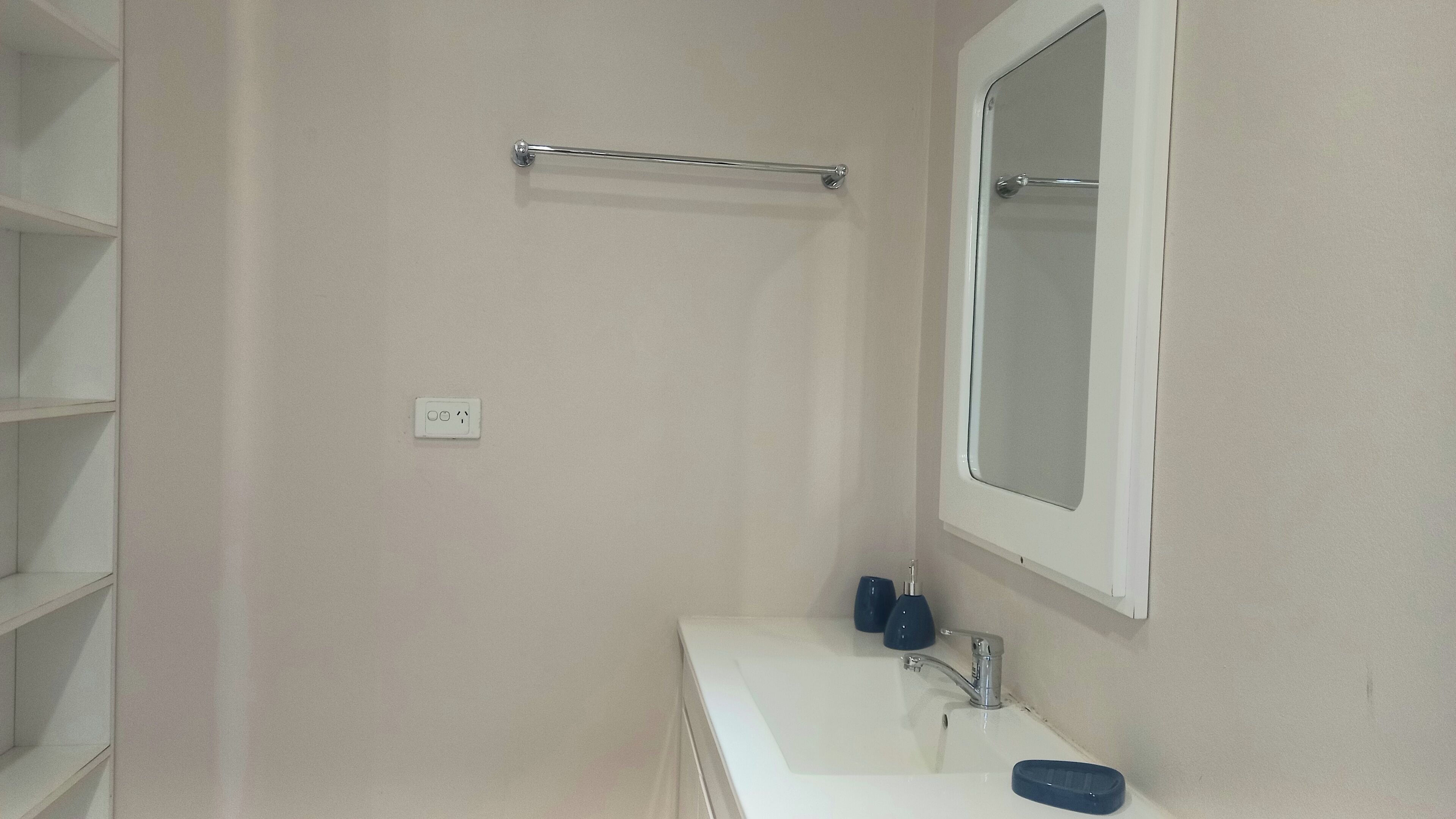 A bathroom with a white sink, a mirror, and a towel rack.