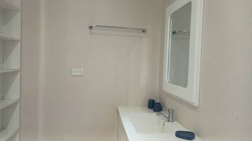 A bathroom with a white sink, a mirror, and a towel rack.