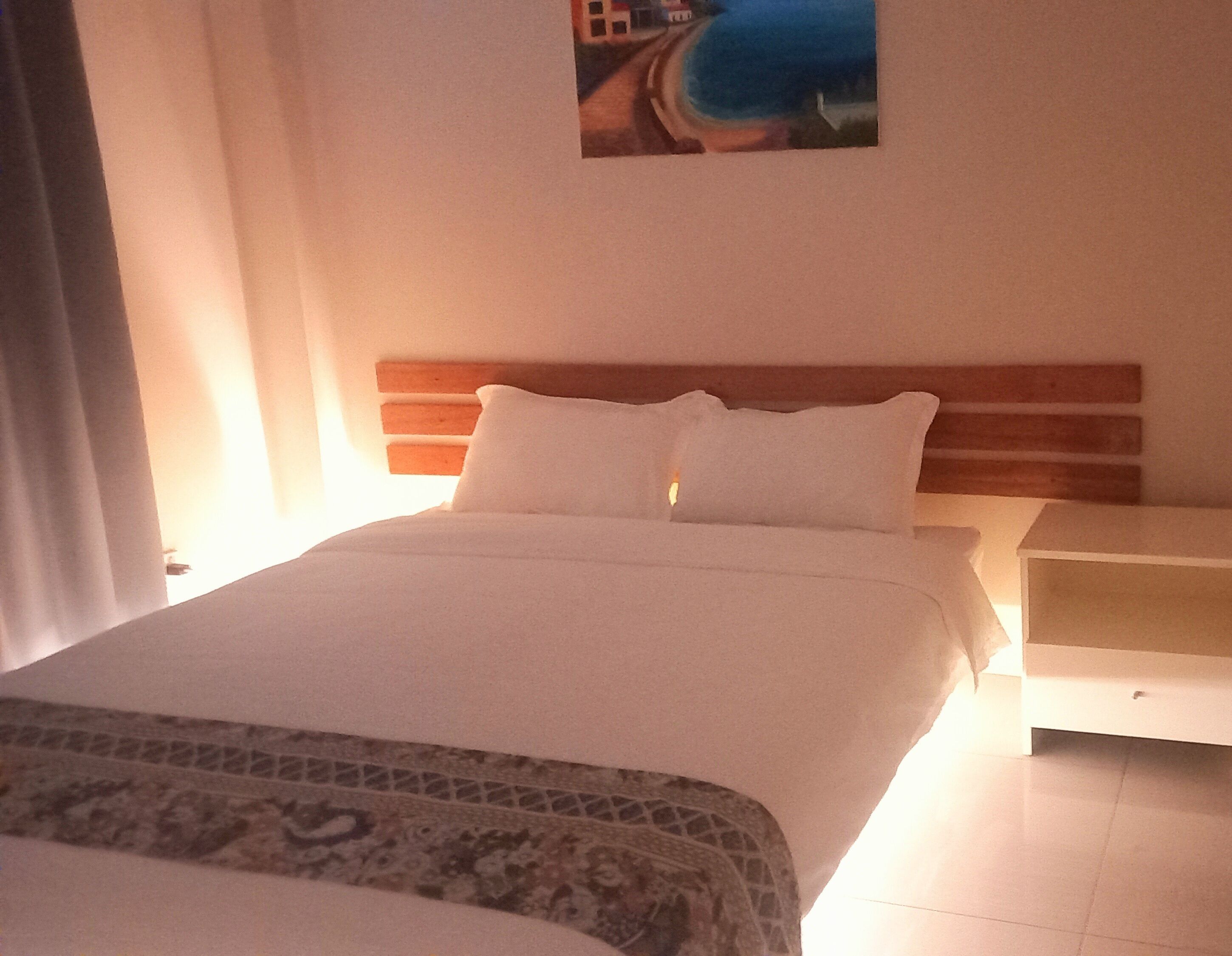 A neatly made bed with a patterned bedspread, a wooden headboard, and a nightstand with a lamp.