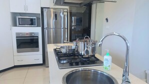 Una cocina moderna con electrodomésticos de acero inoxidable, incluyendo una estufa, horno y microondas.