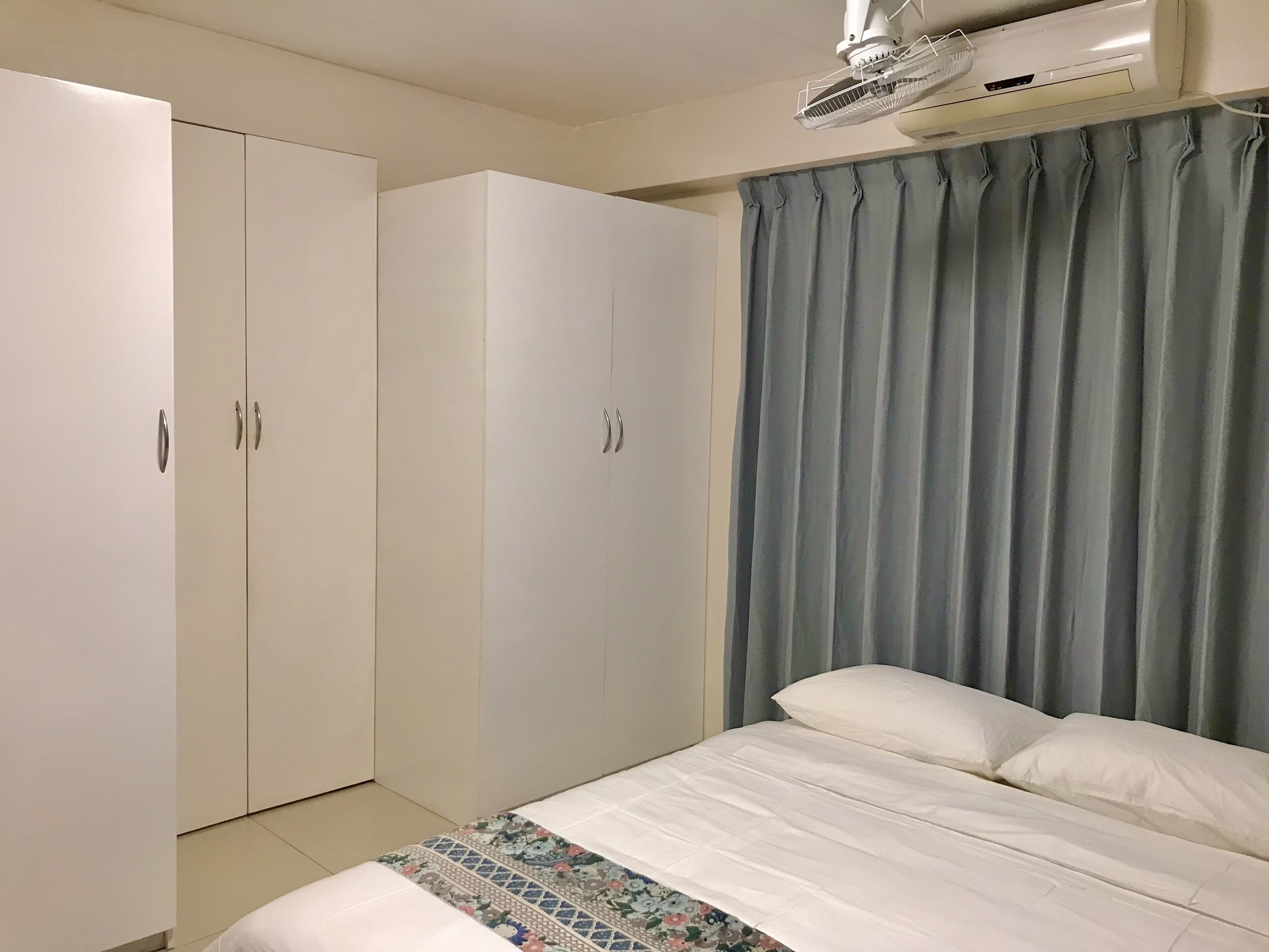 A bedroom with a bed, a wardrobe, and an air conditioning unit.