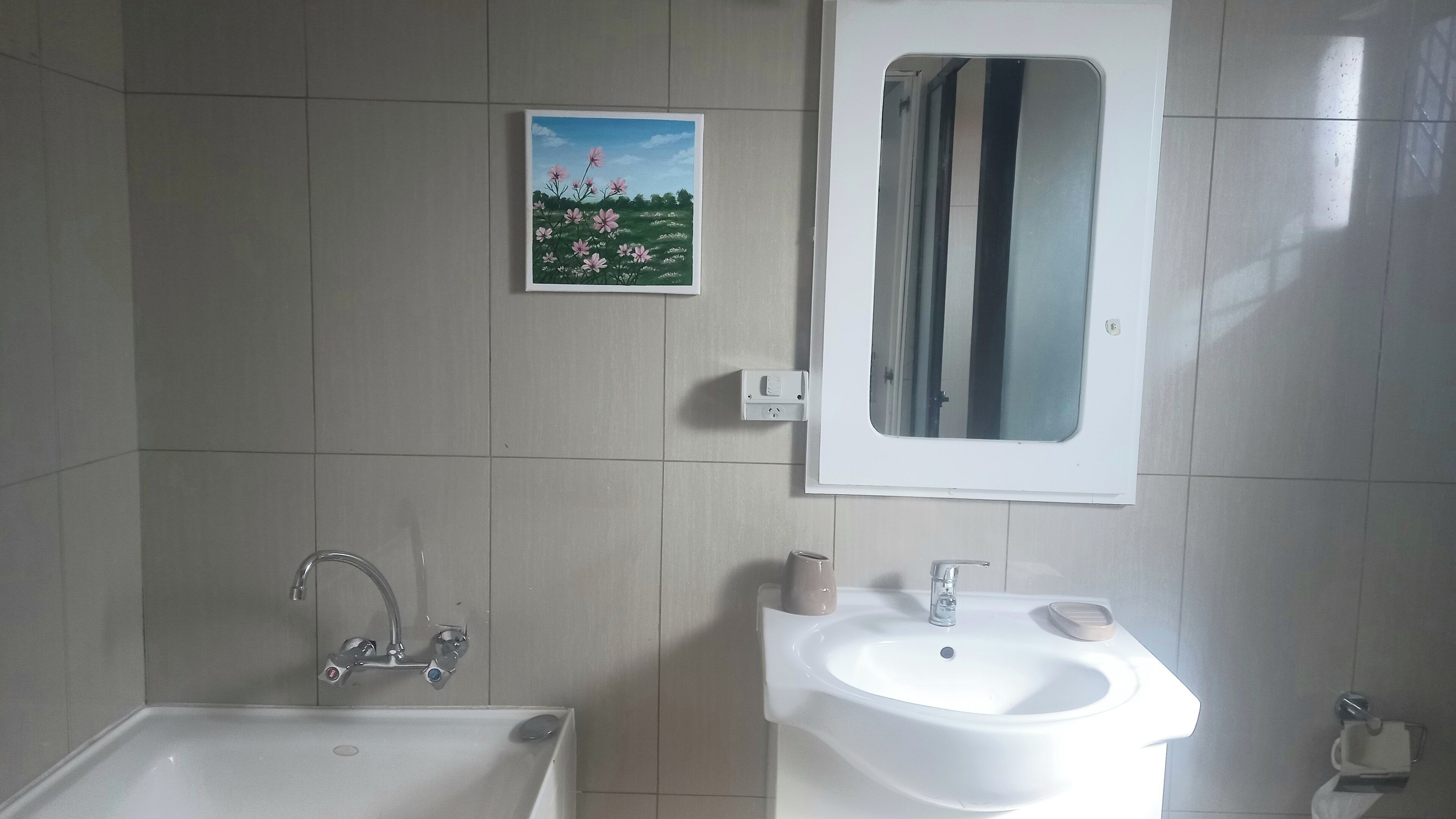 Ein Badezimmer mit Waschbecken, Spiegel und einem Blumenbild an der Wand.