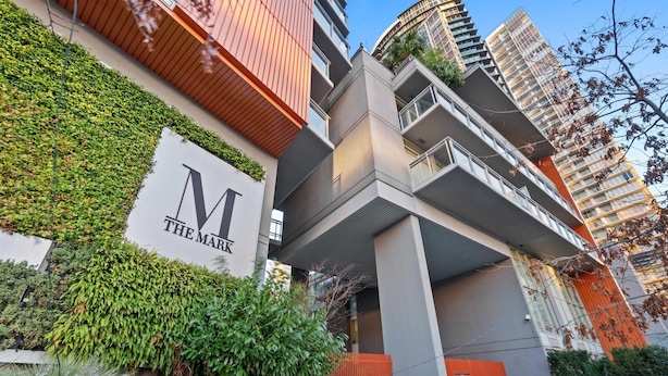 A modern building with a prominent 'M' logo and greenery on the facade.