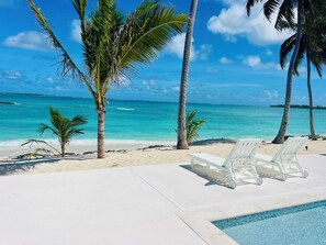 Un espace aménagé au bord de la piscine, avec des chaises longues et une vue sur l’océan.
