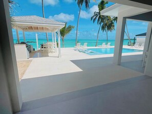 Un espace extérieur abrité comprenant une piscine, des chaises longues et une vue sur l’océan.