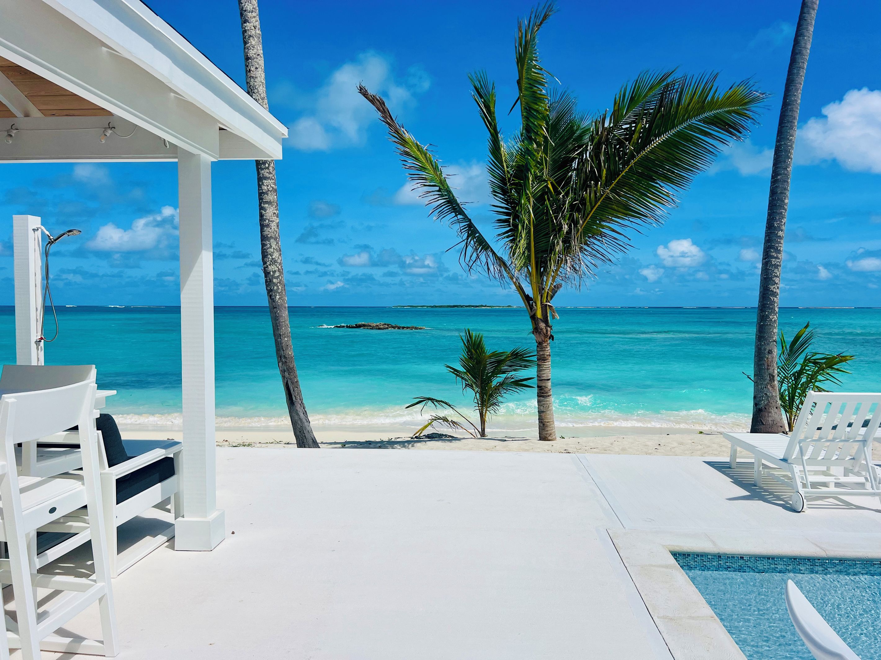 A beachside pool area with lounge chairs and a view of the ocean.
