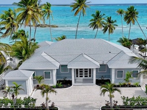 Ein strandnahes Anwesen mit symmetrischer Gestaltung, das einen Mittelpunkt-Eingang, zahlreiche Fenster und eine überdachte Terrasse bietet.