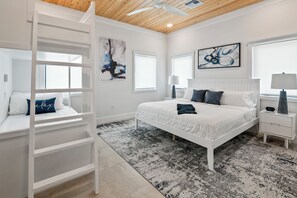 Ein Schlafzimmer mit einem Bett, einem Nachttisch, einer Lampe, einer Leiter und Kunstwerken an den Wänden.