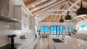 A modern kitchen with white cabinets, a large island, and pendant lighting.