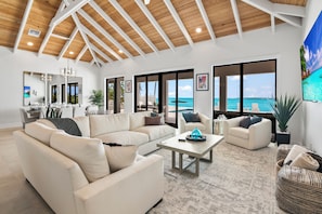 Amplia sala de estar con techo alto, ventanas grandes que ofrecen vistas al océano y un diseño interior moderno.