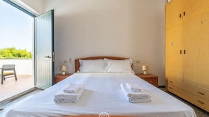 A hotel room with a bed, two bedside tables with lamps, a wardrobe, and a sliding glass door leading to an outdoor area. - La Casa sul Mare (Su Pallosu)