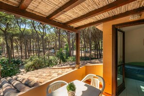 A covered outdoor seating area with a table and chairs, overlooking a forested landscape. - Casa di Marco (Santa Margherita di Pula)