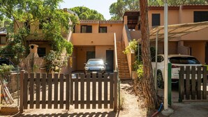 Un edificio residencial con un automóvil estacionado en la entrada, una valla de madera y una escalera que sube al piso superior.