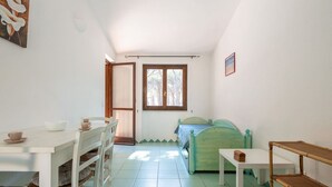 Una habitación con una cama, una mesa, sillas, una ventana y una puerta.