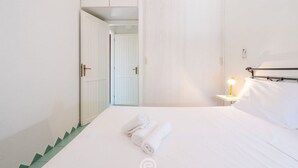 Habitación de hotel con cama, mesita de noche con lámpara y armario con puerta.