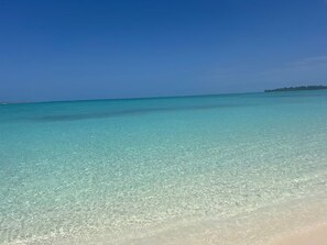 Une plage bordée d’une eau turquoise et cristalline, avec une côte qui s’étend à perte de vue.