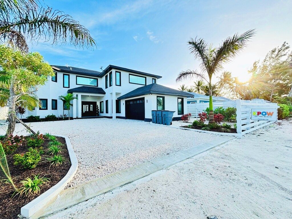 A modern two-story house with a driveway, a garage, and a signboard.