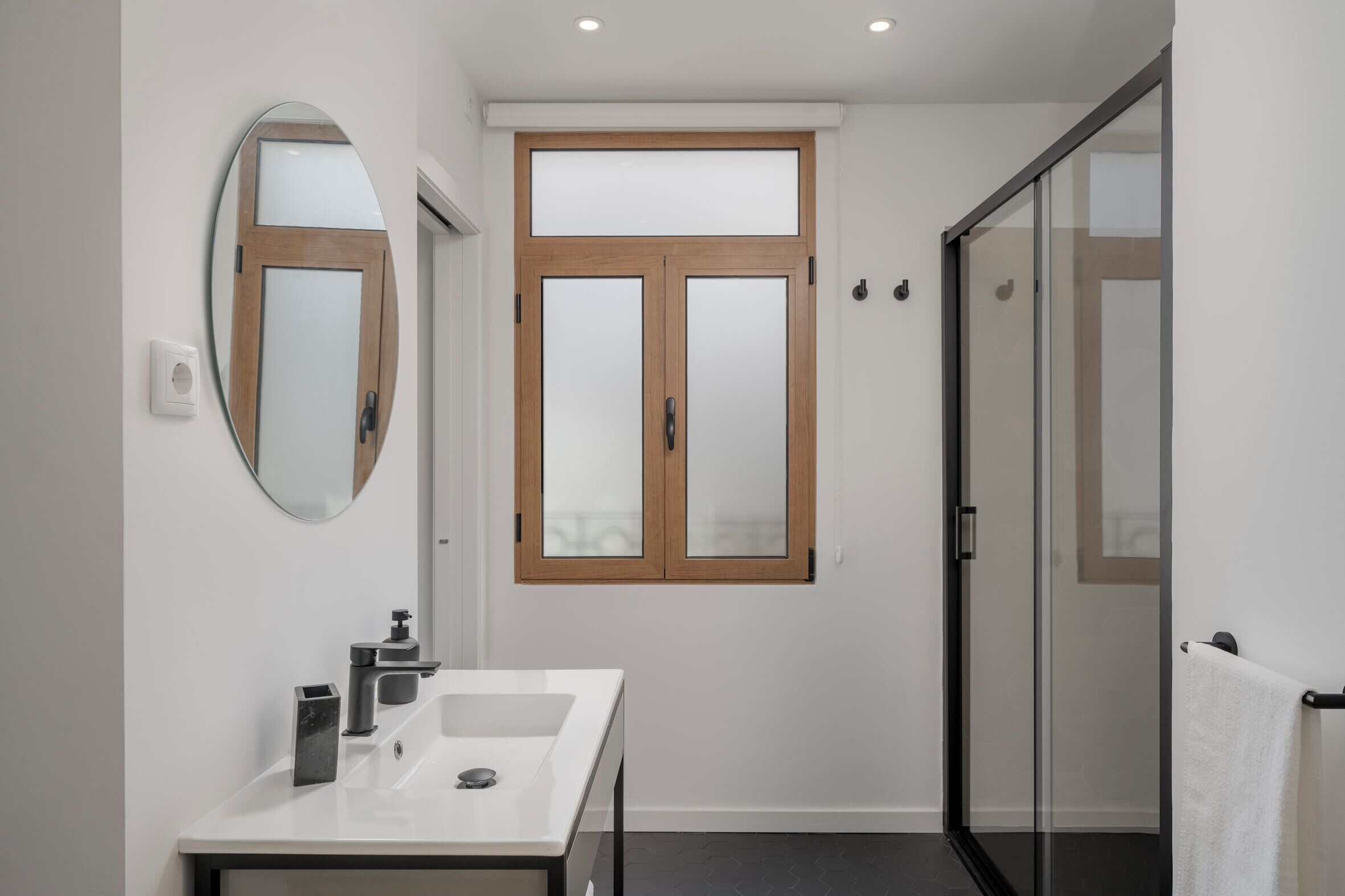 Een moderne badkamer met een wit wastafelmeubel, een grote spiegel en een douchecabine van glas.