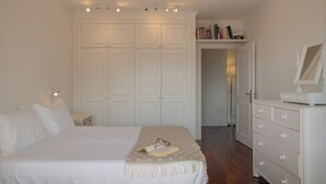 A bedroom with a bed, bedside table, dresser, and a wardrobe.