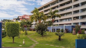 A hotel with a well-maintained garden, multiple balconies, and a modern architectural design.