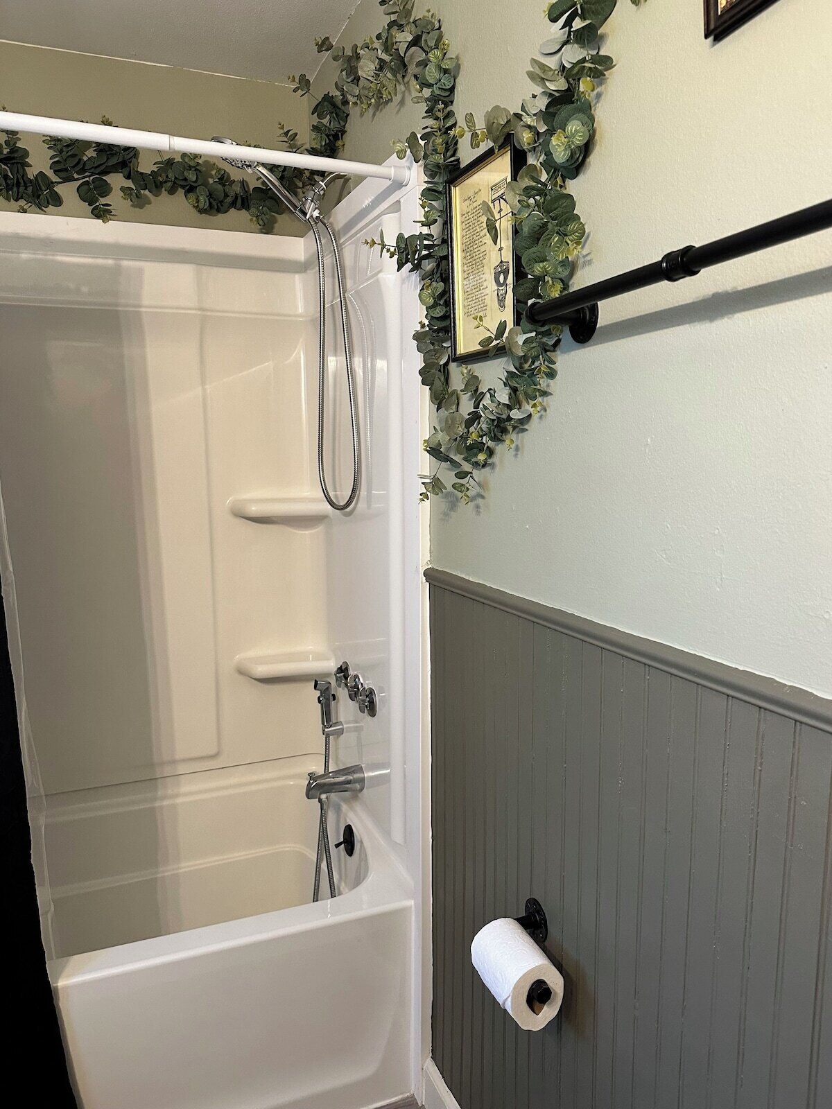 A bathroom with a white bathtub, a showerhead, and a toilet paper holder on the wall.