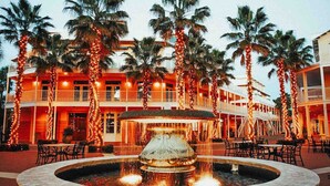 A hotel with a central fountain, palm trees, and outdoor seating areas. - Palm Paradise Unique Home! WALK TO BEACH! 4 POOLS! (Panama City Beach)