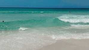 A beach with clear turquoise water and a sandy shore. - Palm Paradise Unique Home! WALK TO BEACH! 4 POOLS! (Panama City Beach)