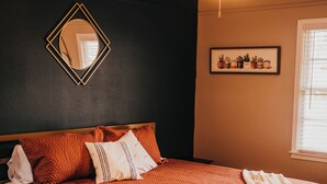 Un dormitorio con cama de madera, ventilador de techo, espejo y ventana con persianas.