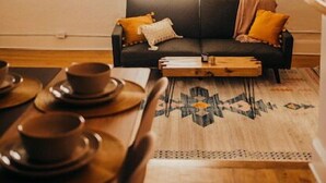 A cozy living room with a dark sofa, a wooden coffee table, and a patterned rug. - Historic Downtown Loft (Waxahachie)