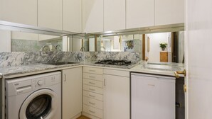 Une cuisine de taille réduite équipée d’un lave-linge, d’un réfrigérateur compact et d’une cuisinière à gaz.