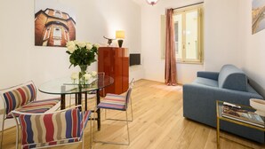 Un salon moderne avec une table à manger en verre, des chaises à rayures, un canapé bleu et un plancher en bois.