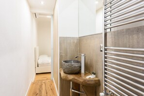 Une salle de bain moderne avec un lavabo en pierre, un plan de toilette en bois et un porte-serviettes.