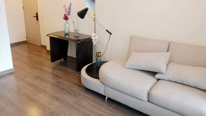 Moderni olohuone, jossa on vaaleanvärinen sohva, tumma puinen sohvapöytä ja lattiavalaisin.