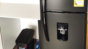 Musta jääkaappi, jossa on kierrätysastia ja kahvinkeittimen säilytyslaatikko.