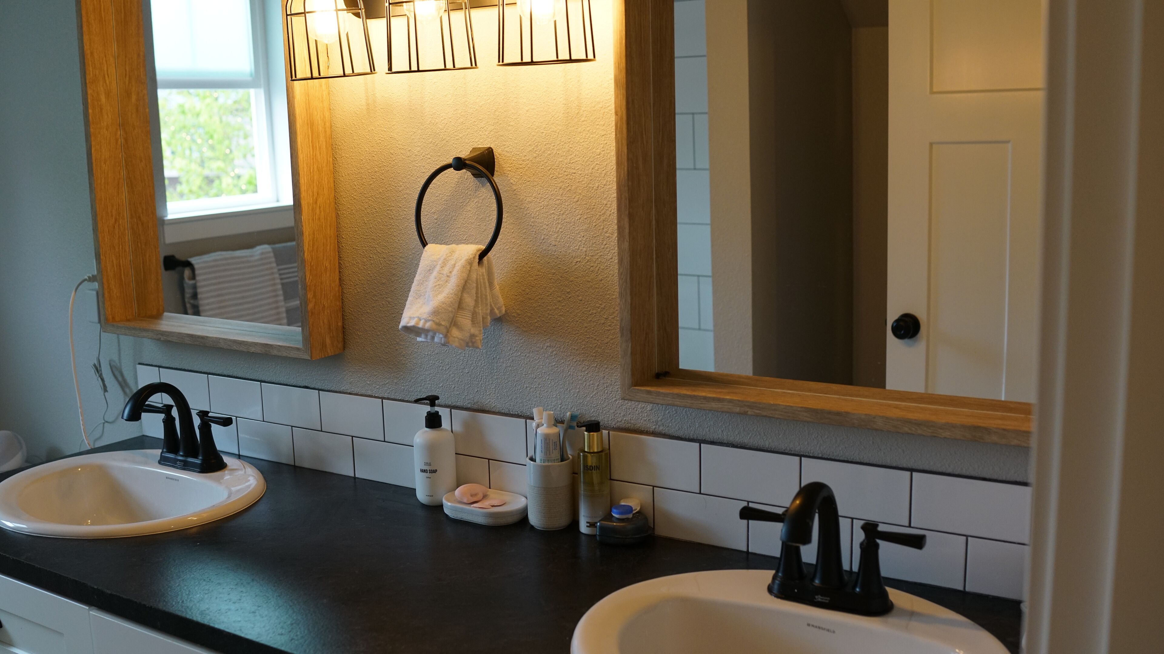 A bathroom with two sinks, a mirror, and a towel rack.