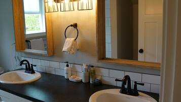 A bathroom with two sinks, a mirror, and a towel rack.
