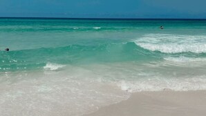 A beach with clear turquoise water and a sandy shore.