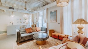 A modern living room with a sofa, round coffee table, and a dining area with a table and chairs.
