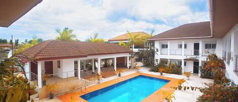 A swimming pool surrounded by potted plants and a covered patio area.