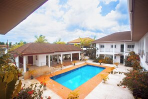A swimming pool surrounded by potted plants and a covered patio area. - BRAGHA APARTMENTS (Sekondi-Takoradi)