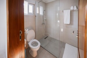 A bathroom with a toilet, shower, and a towel rack. - BRAGHA APARTMENTS (Sekondi-Takoradi)