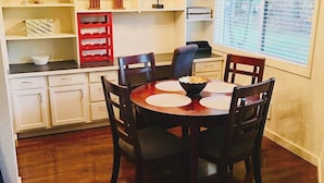 A dining area with a round table, four chairs, and a red storage unit.