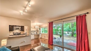 A modern kitchen with a microwave and stove, a dining area with a table and chairs, and a large sliding glass door leading to a backyard.